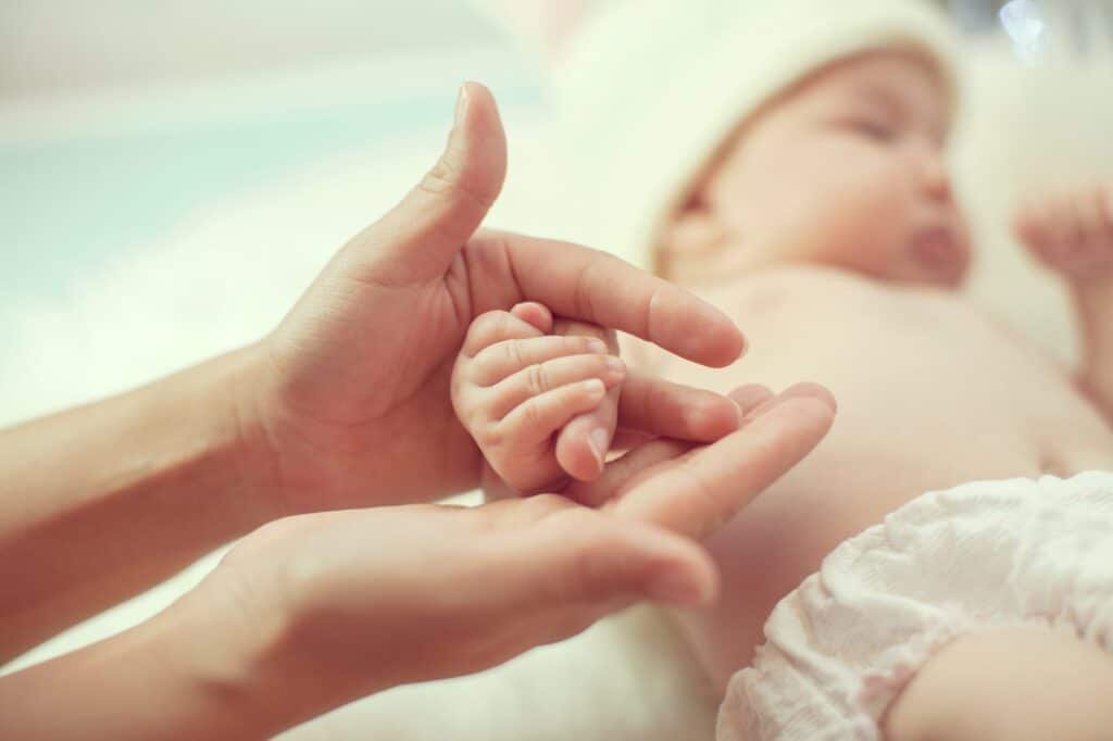 Mãe segura nas mãos do seu bebê